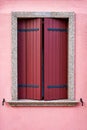 Window with closed red shutter on pink wall. Italy, Venice, Burano island. Royalty Free Stock Photo