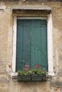 Window with closed shutters and flowers.