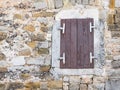 Window with closed window shutters in a wall of rough rocks