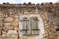 Window with closed wooden shutters on old abandoned traditional stone house Royalty Free Stock Photo