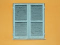 Window with closed wooden shutters on orange wall Royalty Free Stock Photo