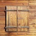 Window closed by wooden shutters on a wooden wall. Forged metal curtains. Ancient architecture and traditional design. The use of Royalty Free Stock Photo