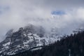 Window in the clouds shows the mountain top covered in snow and some blue sky Royalty Free Stock Photo