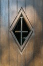A window with cobwebs and an iron cross in a wooden door
