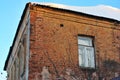 The window on the corner the old brick building, roof covered with snow on blue sky background Royalty Free Stock Photo