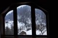 Window in the countryside with a view of the rural house and a mountainous winter landscape outside the window. Royalty Free Stock Photo