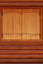 The window is covered with wooden shutters. Wall of a rural log house. Bright light back Royalty Free Stock Photo