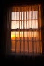 Window with a curtain drawn and the sun setting Royalty Free Stock Photo
