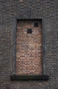 A window in a dark brick wall is lined with red brick with two holes for ventilation Royalty Free Stock Photo
