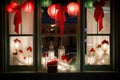 window display with red and green lanterns, wreath, and bow on a white curtain