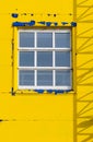 A window on the facade with peeling yellow paint.