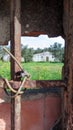 A window in the fence with a lattice, sealed with bricks, in which there is a hole overlooking the house Royalty Free Stock Photo