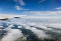 From window of flying plane airplane wing glides gracefully over sea of clouds