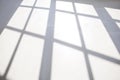 Window frames shadow on white floor in empty room. Background from light and shadow on white