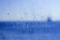 Window glass with drops and blue blurs