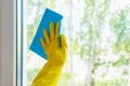 Window glass washing. A hand in a yellow glove washes the window with a blue rag Royalty Free Stock Photo