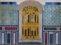 Window with golden railings and classical oriental design on tiled wall.