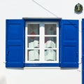Window of a greek house with blue shutters