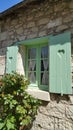 Window with green frames and wooden shutters and lace curtains