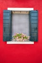 Window with green shutters and pink flowers in the pot. Italy, Venice, Burano Royalty Free Stock Photo