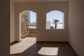 Window hole in the white stone wall of a building overlooking the Red Sea and a palm tree on a tropical beach in resort town Sharm Royalty Free Stock Photo