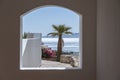 Window hole in the white stone wall of a building overlooking the Red Sea and a palm tree on a tropical beach in resort town Sharm Royalty Free Stock Photo
