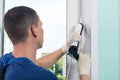 A window installation wizard finishes his work by smearing the joints with sealant, rear view