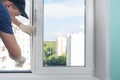 Window installation worker inserts glass into the frame and fastens it with a rubber mallet, rear view Royalty Free Stock Photo