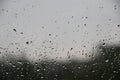 Window with large drops of rain on a gray urban background. The first summer storm