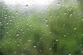 Window with large drops of rain on a green, urban background. summer rainy day, rain drops on the window glass large Royalty Free Stock Photo
