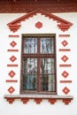 A window with a lattice framed by a beautiful pattern of bricks on the background of the white wall of an old building. Royalty Free Stock Photo