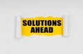 A window is made in the paper, where on a yellow background the inscription - Solutions Ahead