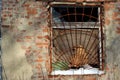 The window of the old brick building covered with rusty iron grate, snow on window sill