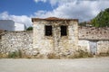 The window of an old stone house with a broken window in the foreground, ruins of an old house in the village.