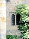 A window in an old stone wall and a green tree beside it Royalty Free Stock Photo
