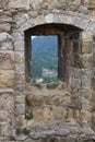 A window in an old stone wall overlooking the forest and houses, the ruins of an old castle Royalty Free Stock Photo