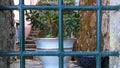 A window in an old stone wall with a thick old steel lattice, painted black, inside, on the window, a pot of flowers Royalty Free Stock Photo