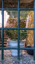 A window in an old stone wall with a thick old steel lattice, painted black, inside, on the window, a pot of flowers Royalty Free Stock Photo