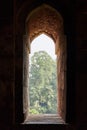 Window opening of ancient indian tomb with green park view, old stone window to green garden view