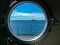 Window port of navy ship with destroyer sails beside the observer`s ship. Royalty Free Stock Photo