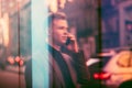 Window reflection of successful young adult businessman talks on the cell phone on city street. Royalty Free Stock Photo