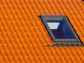 Window on roof of house with orange roof tiles on a background of blue sky Royalty Free Stock Photo