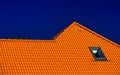 Window on roof of house with orange roof tiles on a background of blue sky Royalty Free Stock Photo