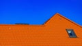 Window on roof of house with orange roof tiles on a background of blue sky Royalty Free Stock Photo