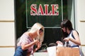 Two happy fashion women with shopping bags at the mall window Royalty Free Stock Photo