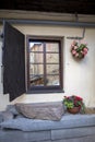 Window with shutters of the old house and hanging pots with begonias