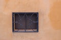 Window with steel shutters with grill on a yellow wall Royalty Free Stock Photo