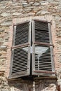 window in a stone wall with old weathered wooden shutters almost closed to shut out the hot summer sun Royalty Free Stock Photo