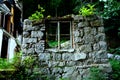 A window in the stone wall of the ruins of a mountain house damaged by an earthquake and a landslide in the mountains. a hut destr