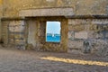 Window in a stone wall showing the sea and a boat